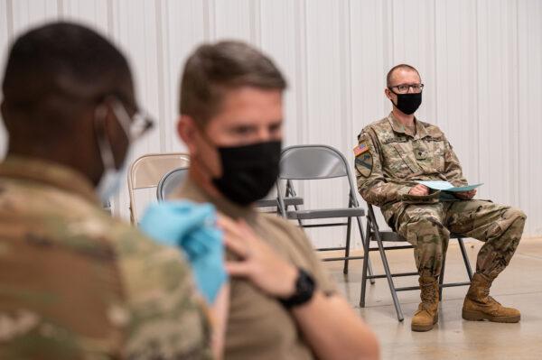  A soldier watches another soldier receive his COVID-19 vaccination from Army Preventive Medical Services in Fort Knox, Ky., on Sept. 9, 2021. (Jon Cherry/Getty Images)