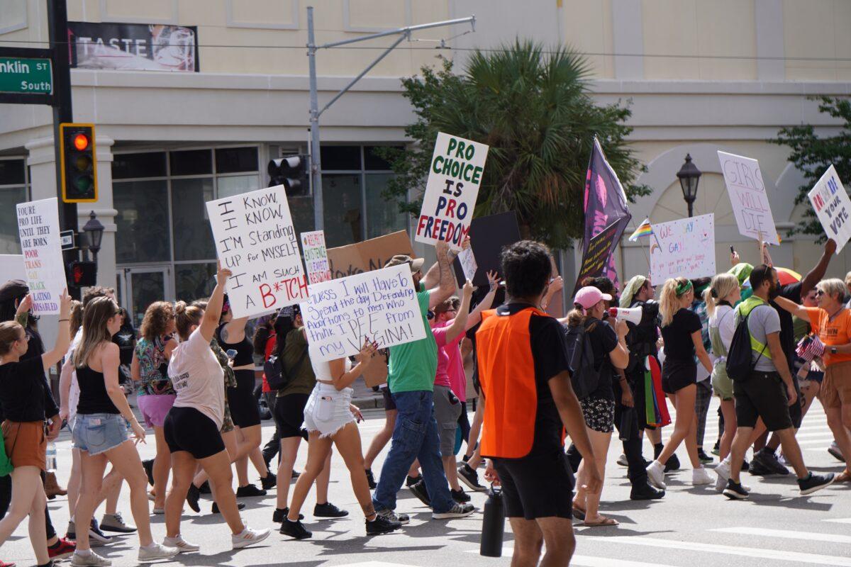 Protesters against restricted access to abortions and the recently passed Parental Rights in Education law in Florida march toward a conservative youth conference in Tampa on July 23, 2022. (Natasha Holt/The Epoch Times)