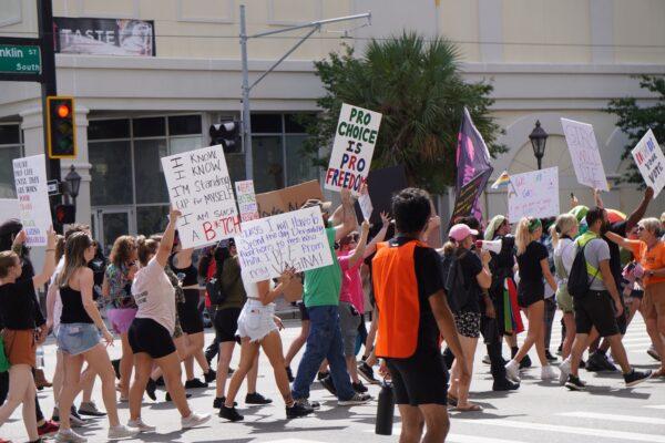 Protesters angry about restricted access to abortions and the recently passed Parental Rights in Education law in Florida march toward a conservative youth conference in Tampa on July 23, 2022. (Natasha Holt/The Epoch Times)