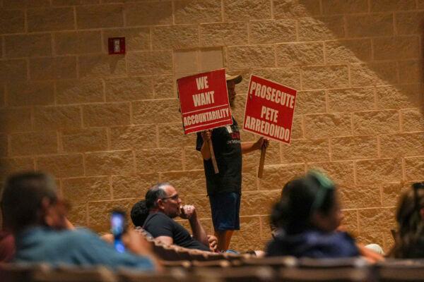 Uvalde resident Michael Brown holds signs at a Uvalde Consolidated Independent School District board meeting in Uvalde, Texas, on July 18, 2022. (Charlotte Cuthbertson/The Epoch Times)