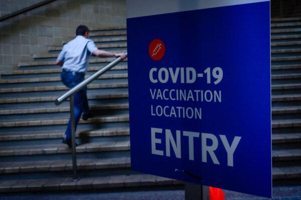 A man walks past signage at a COVID-19 vaccination hub at the Brisbane Convention and Exhibition Centre in Australia, on Aug. 17, 2021. (Patrick Hamilton/AFP via Getty Images)