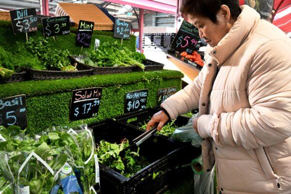 A shopper places salad mix in a bag at Victoria Market in Melbourne, Australia, on July 5, 2022. (William West/AFP via Getty Images)