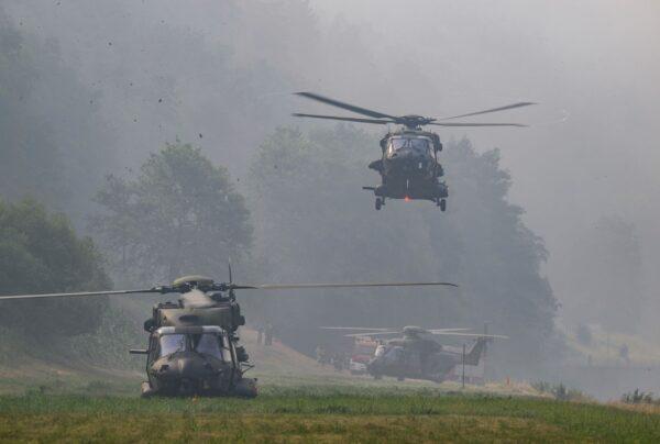 Bundeswehr helicopters land on the banks of the Elbe to help with firefighting efforts in the Saxon Switzerland National Park, Schmilka, Germany on July 28, 2022. (Robert Michael/dpa via AP)