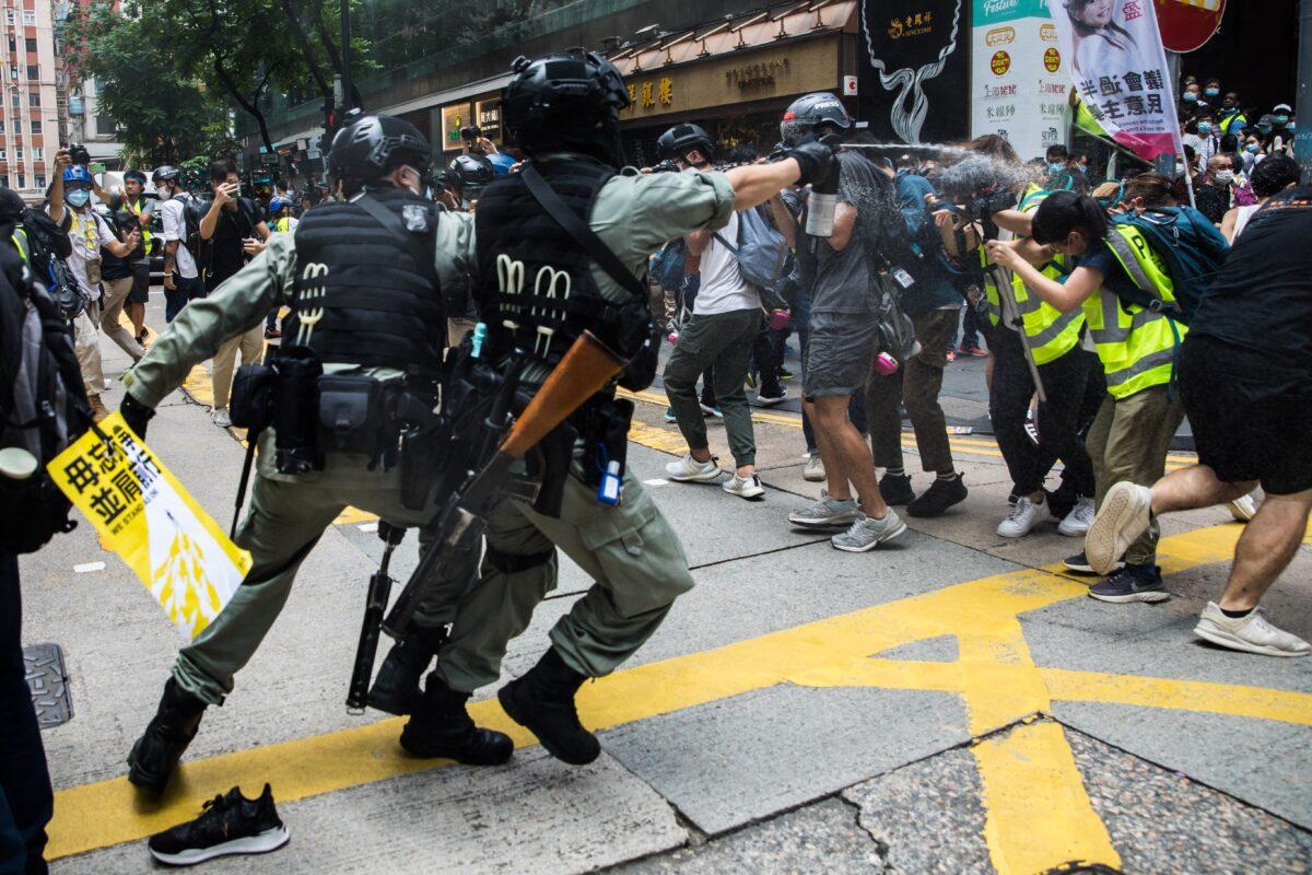Riot police (L) deploy pepper spray toward journalists (R) as protesters gathered for a rally against a new national security law in Hong Kong on July 1, 2020, the 23rd anniversary of the city's handover from Britain to China.(Dale de la Rey/AFP via Getty Images)