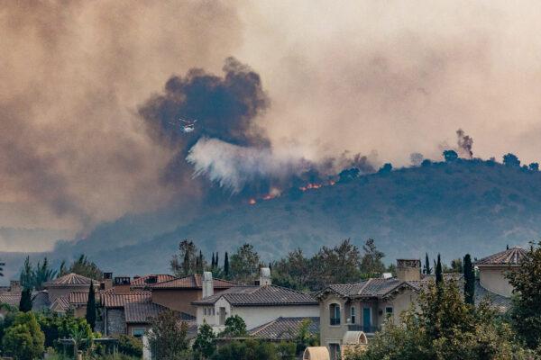 A fire helicopter drops water on the Blueridge fire as it burns near homes in Chino Hiils, Calif., on Oct. 27, 2020. (John Fredricks/The Epoch Times)