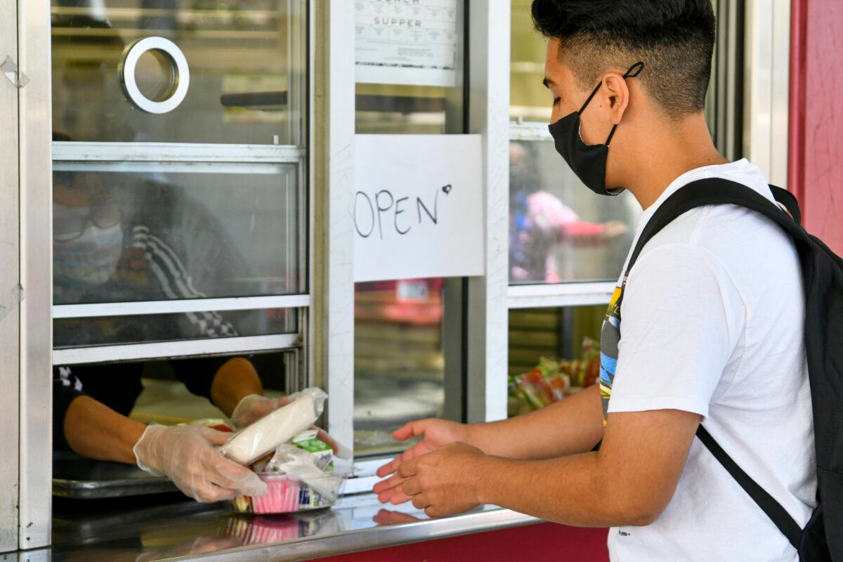 A student receives a pre-packaged lunch at Hollywood High School in Los Angeles on April 27, 2021. (Rodin Eckenroth/Getty Images)