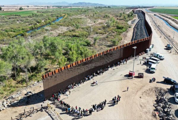 Illegal immigrants wait in line to be processed by the U.S. Border Patrol after crossing through a gap in the U.S.-Mexico border barrier in Yuma, Ariz., on May 21, 2022. (Mario Tama/Getty Images)