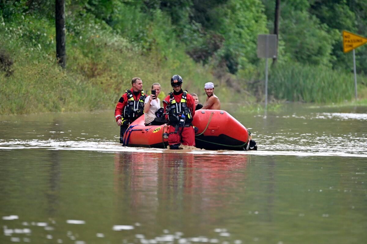 Members of the Winchester, Ky., Fire Department walk inflatable boats across flood waters over Ky. State Road 15 in Jackson, Ky., on July 28, 2022, to pick up people stranded by the floodwaters. (Timothy D. Easley/AP Photo)