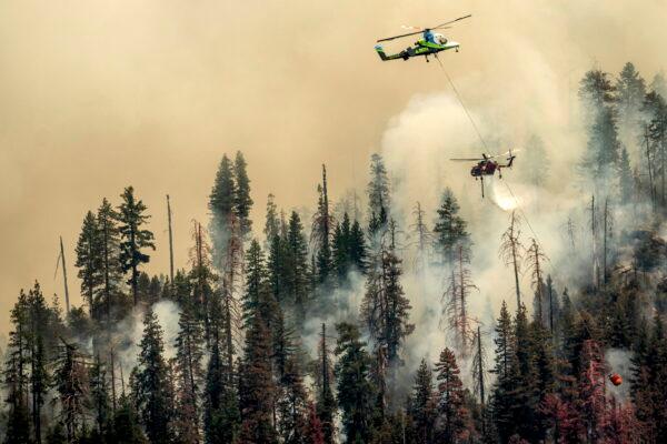Seen from unincorporated Mariposa County, Calif., a helicopter drops water on the Washburn Fire burning in Yosemite National Park on Saturday, July 9, 2022. (Noah Berger/AP Photo)