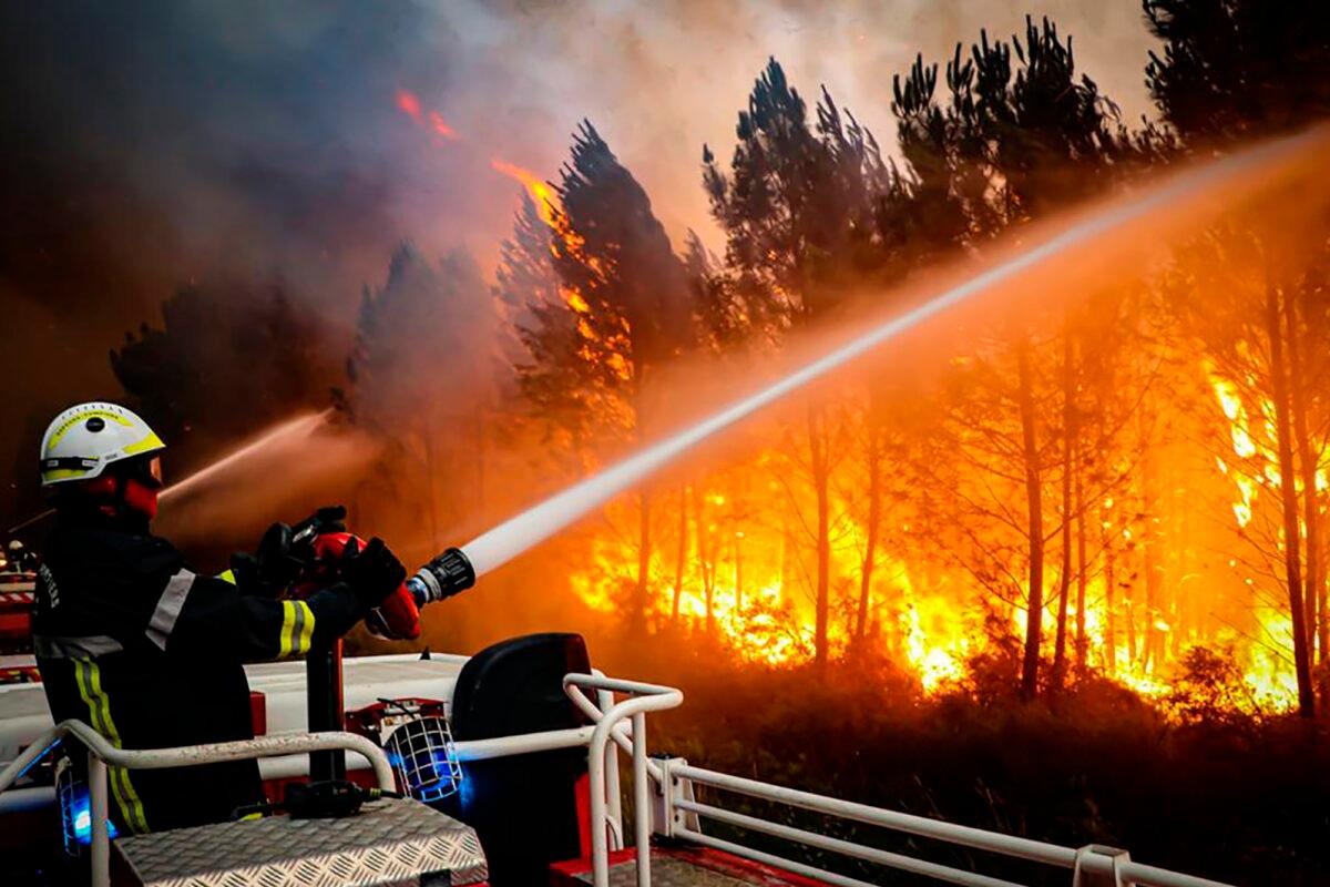 Firefighters using hose to fight a wildfire near Landiras, southwestern France, on July 14, 2022. (SDIS 33 via AP)