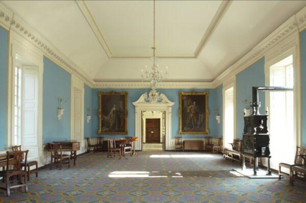 The ballroom and the supper room (not shown) were added in 1750 to accommodate receptions at the Palace. Musicians playing piano forte and harpsichord entertained the gatherings. The “warming machine,” on the right, warmed the room.  The colors were inspired by English royal chambers. A Baroque pedimented doorway leads to the supper room. (J.H. Smith/Cartio)