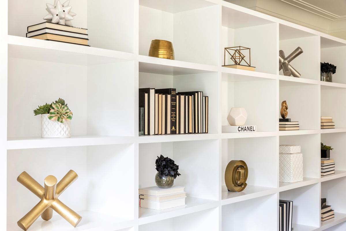 A minimal color palette of black and white, paired with brass accents, creates appealing décor vignettes on this bookcase. (Scott Morris/Cathy Hobbs/TNS)