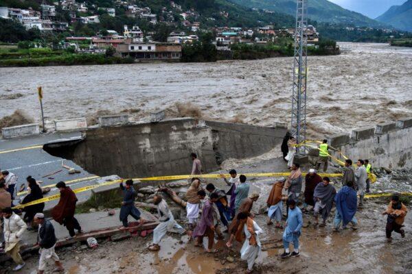People gather in front of a road damaged by flood waters following heavy monsoon rains in the Madian area in Pakistan's northern Swat Valley on Aug. 27, 2022. (Abdul Majeed/AFP via Getty Images)