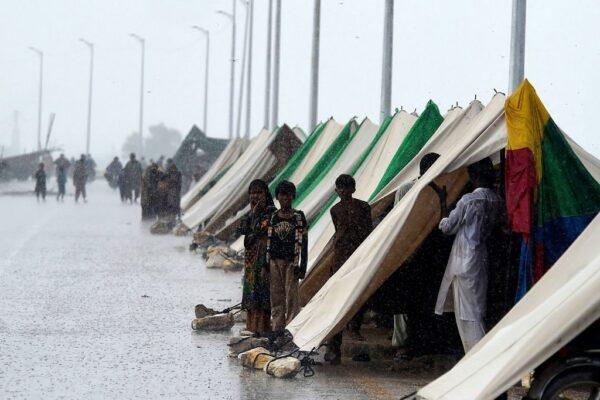 People who fled their flood-hit homes stand outside temporary tents set along a road during a heavy monsoon rainfall in Sukkur of Sindh Province, Pakistan, on Aug. 27, 2022. (Asif Hassan/AFP via Getty Images)