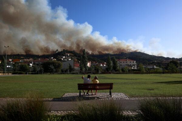 People watch as smoke rises from a wildfire in Venda do Pinheiro, Mafra, Portugal, on July 31, 2022. (Pedro Nunes/Reuters)