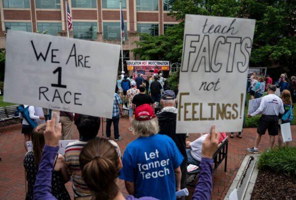 People hold up signs objecting to critical race theory (CRT) being taught in area schools during a protest outside the Loudoun County Government center in Leesburg, Va., on June 12, 2021. (Andrew Caballero-Reynolds/AFP via Getty Images)
