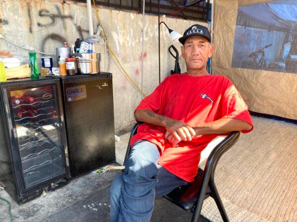 Through charitable donations, Fernando Sanchez has been able to transform a bad situation on Skid Row into a livable one. Here, he sits inside his secondary storage tent on July 26, 2022. (Allan Stein/The Epoch Times)