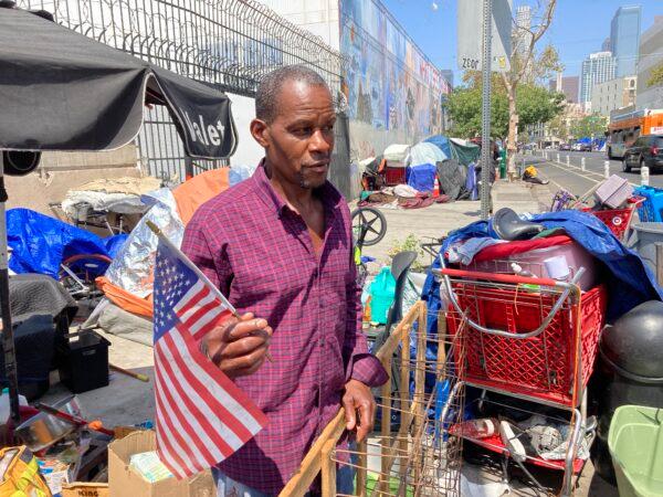 A man who goes by the name Soul Brother holds one of his important possessions—an American flag—on July 26, 2022. (Allan Stein/The Epoch Times)