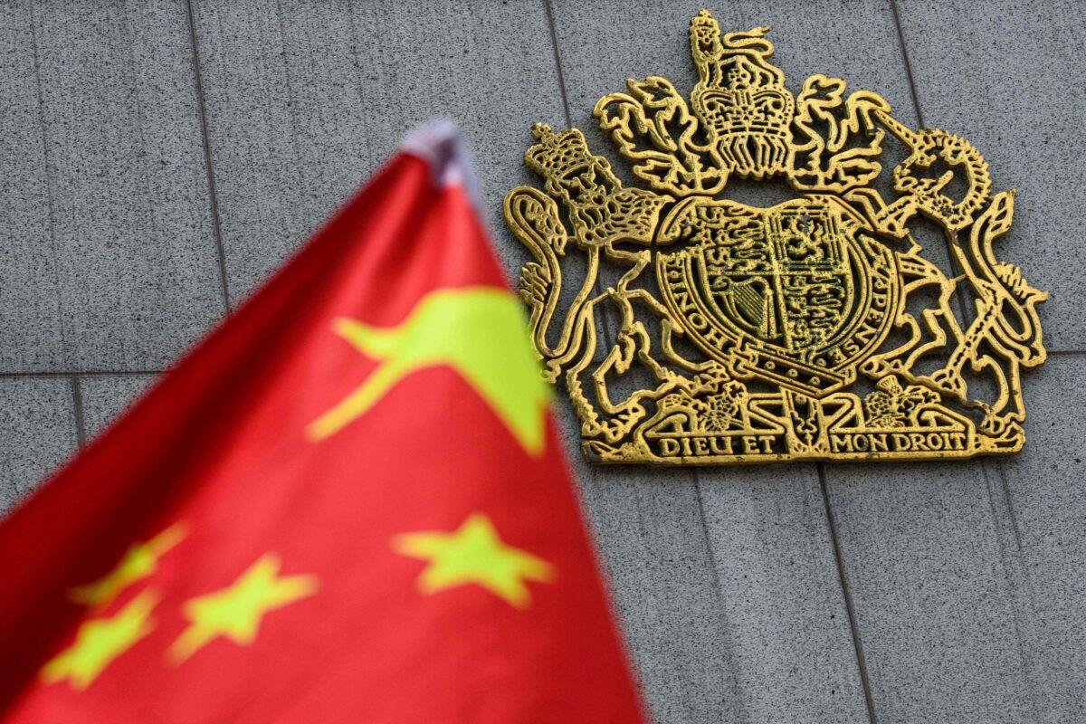 The royal coat of arms of the United Kingdom (R) is seen next to the national flag of China as pro-Beijing activists gather outside the British Consulate-General to protest against the use of the British National (Overseas) passport in Hong Kong on Feb. 1, 2021. (Anthony Wallace/AFP via Getty Images)