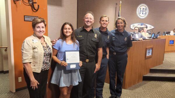 Elizabeth Felten (2nd L) was honored by Mayor Barbara Delgleize (L) and Marine Safety Battalion Chief Doug Leach (C) at the Huntington Beach City Council meeting in Huntington Beach on Aug. 2, 2022. (Courtesy of the City of Huntington Beach)