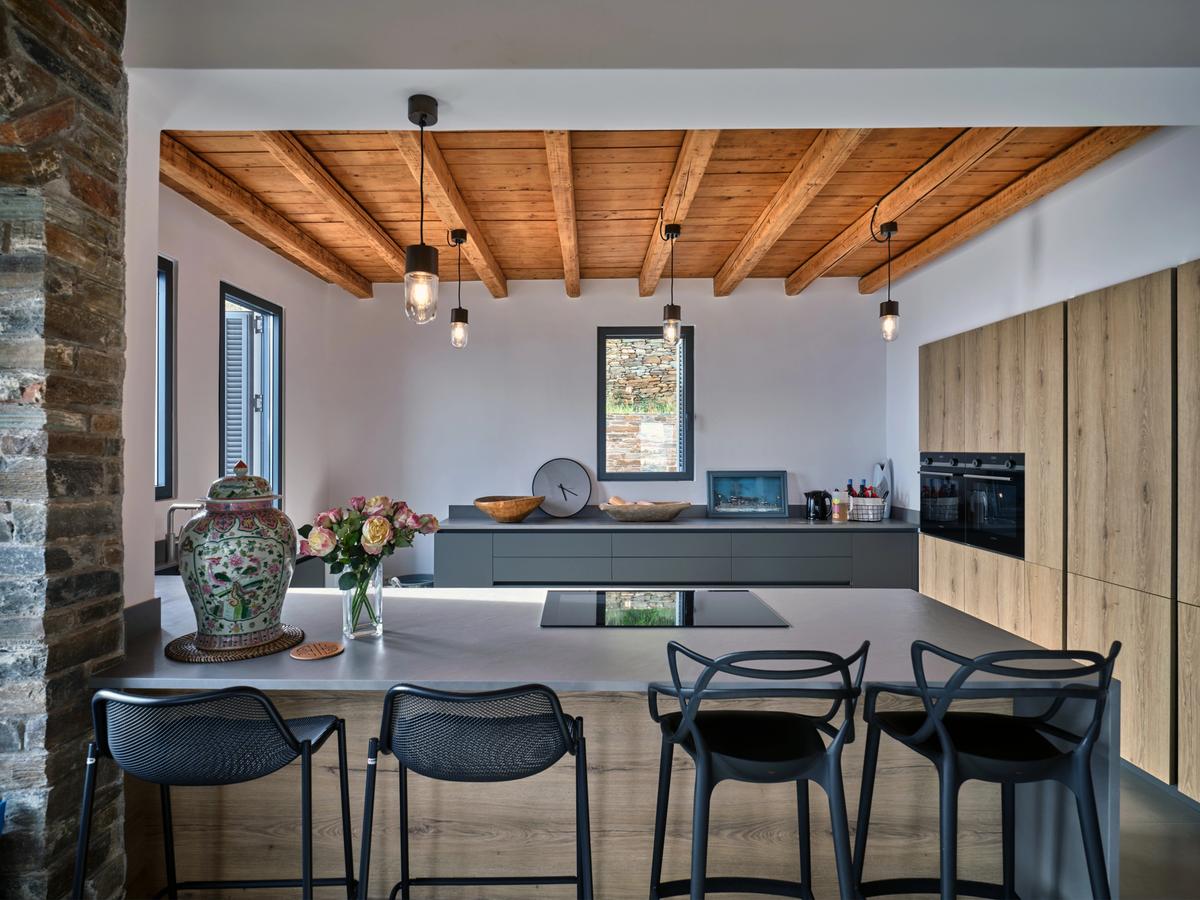 The airy kitchen space is highly functional with ample room to prepare meals. A breakfast bar separates the cooking and family/guest dining area, and the terrace beyond. (Courtesy of Greece Sotheby's International Realty)