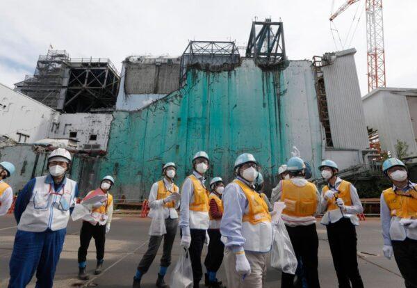 In this picture taken on July 27, 2018, foreign journalists receive information about decommissioning works between reactor unit 2 and unit 3 (in background) at the tsunami-crippled Fukushima Dai-ichi nuclear power plant in Okuma, Fukushima prefecture, Japan. (Kimimasa Mayama/AFP via Getty Images)