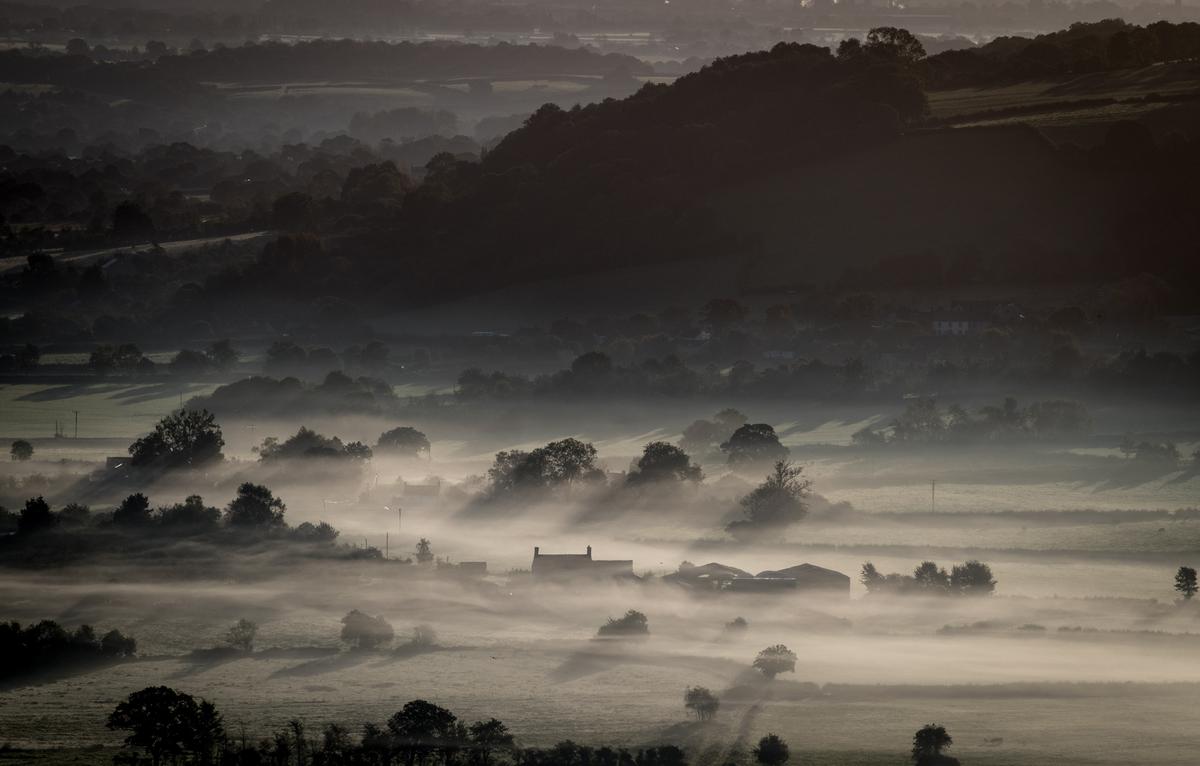 A farm house is surrounded by early morning mist lingering in fields as the autumn sun rises over the Somerset Levels, England on Sept. 22, 2017. (Matt Cardy/Getty Images)