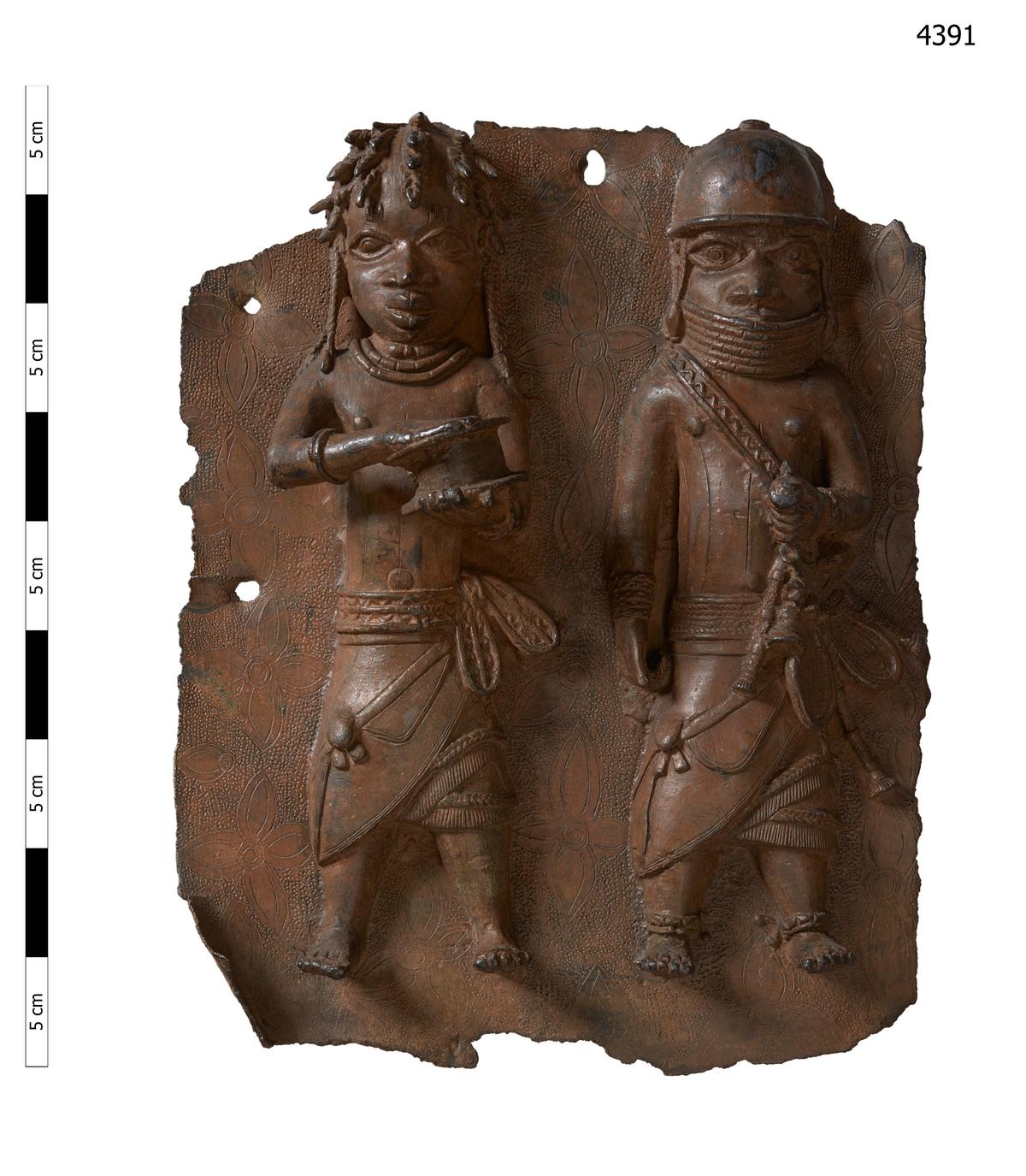 A brass plaque depicting a war chief and a royal military priest carrying a leather gift box. (Courtesy of Horniman Museum and Gardens via AP)