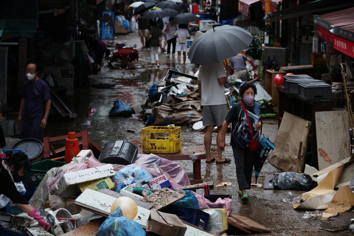 People make their way through a road that was flooded after torrential rain, at a traditional market in Seoul, South Korea, on Aug. 9, 2022. (Kim Hong-Ji/Reuters)