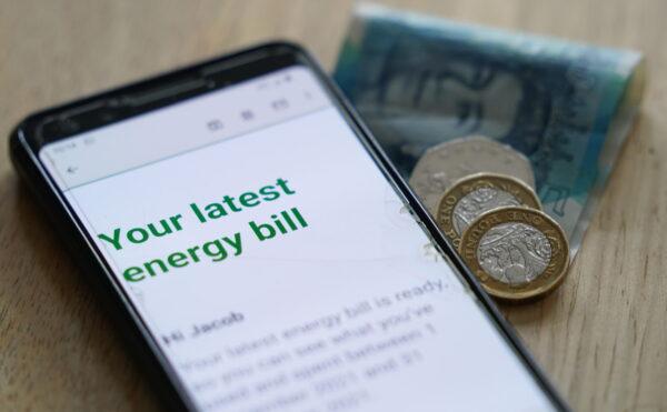 Undated photo showing some cash in Sterling with a mobile photo displaying the words "your latest energy bill." (Jacob King/PA Media)