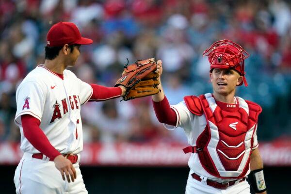 Los Angeles Angels starting pitcher Shohei Ohtani, left, taps gloves with Max Stassi at the end of the top of the second inning of a baseball game against the Seattle Mariners in Anaheim, on Aug. 15, 2022. (Marcio Jose Sanchez/AP Photo)