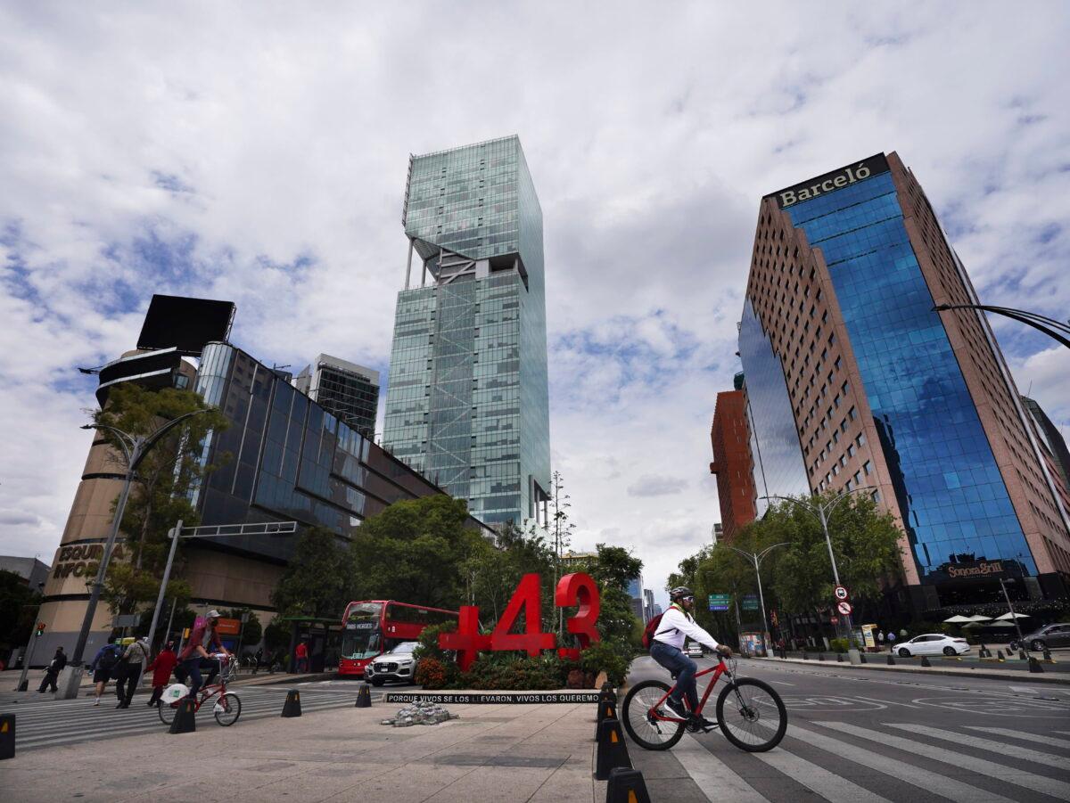 A bicyclist pedals past a monument dedicated to the 2014 disappearances of 43 students from a Guerrero state radical teacher college, in Mexico City, on Aug. 20, 2022. (Marco Ugarte/AP Photo)