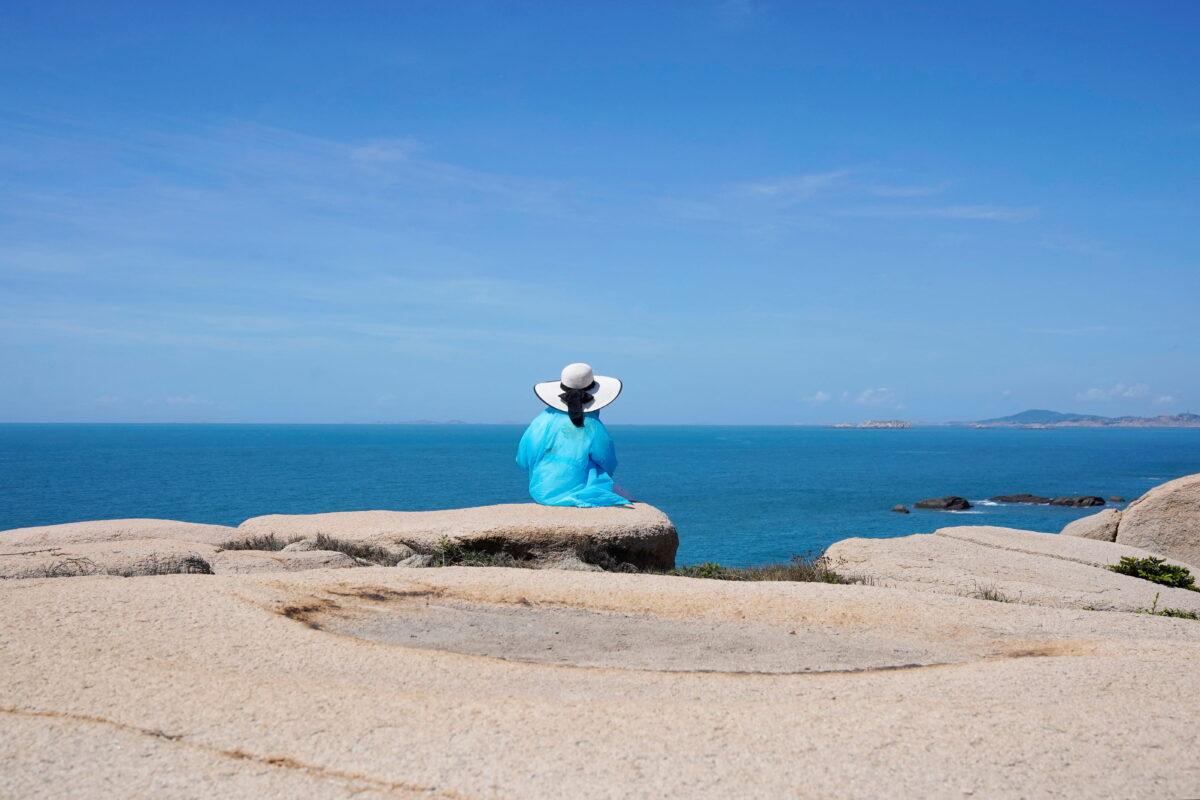 A tourist sits facing the Taiwan Strait at the 68-nautical-mile scenic spot, one of mainland China's closest points to Taiwan, in Pingtan Island, Fujian Province, China, on Aug. 5, 2022. (Aly Song/Reuters)