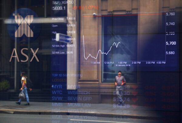 Pedestrians are reflected in a window in front of a board displaying stock prices at the Australian Securities Exchange (ASX) in Sydney, Australia, on Feb. 9, 2018. (David Gray/Reuters)