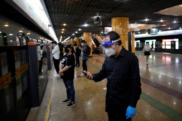 A man wearing protective gear checks his mobile phone at a subway station, after the COVID-19 lockdown was lifted in Shanghai, China, on June 2, 2022. (Aly Song/Reuters)