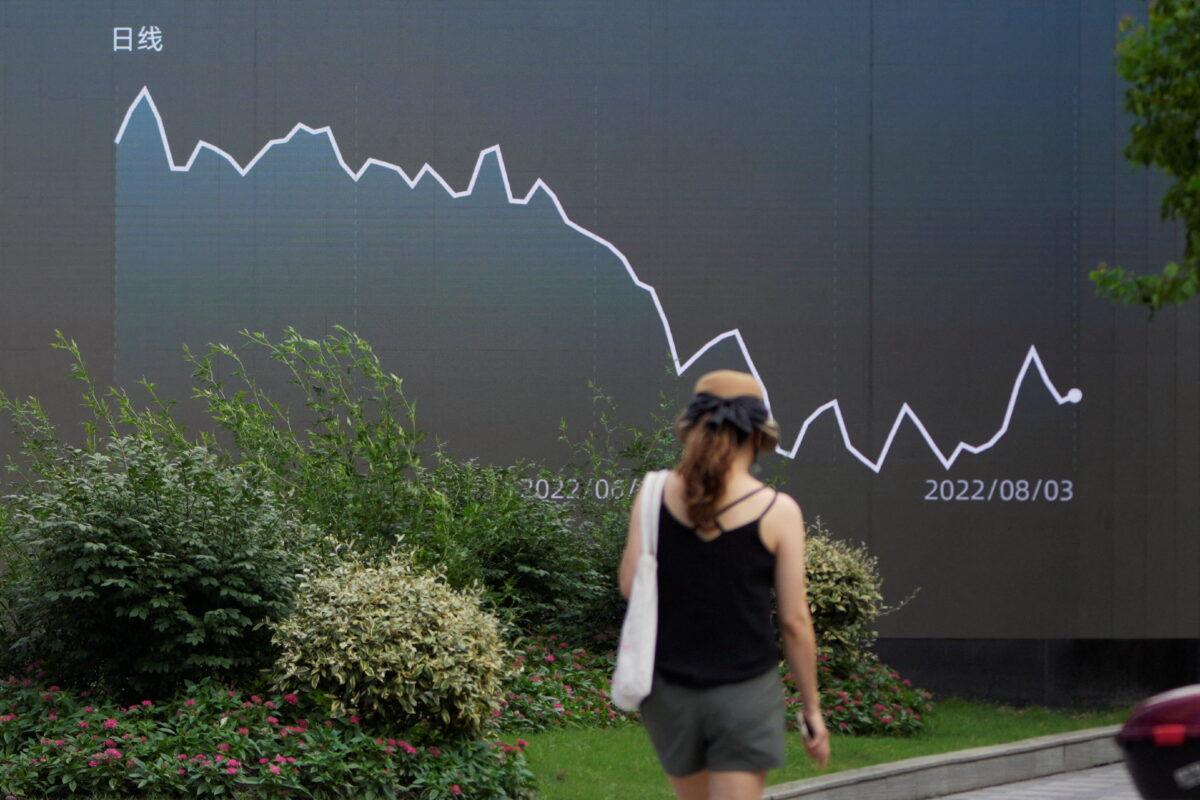 A pedestrian walks past a giant display showing a stock graph in Shanghai, China, on Aug. 3, 2022. (Aly Song/Reuters)