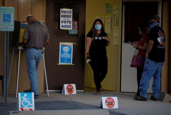 A voter, left, fills in his ballot at a polling booth as other voters wait in line in Marana, Ariz., on Nov. 3, 2020. (REUTERS/Cheney Orr/File Photo)