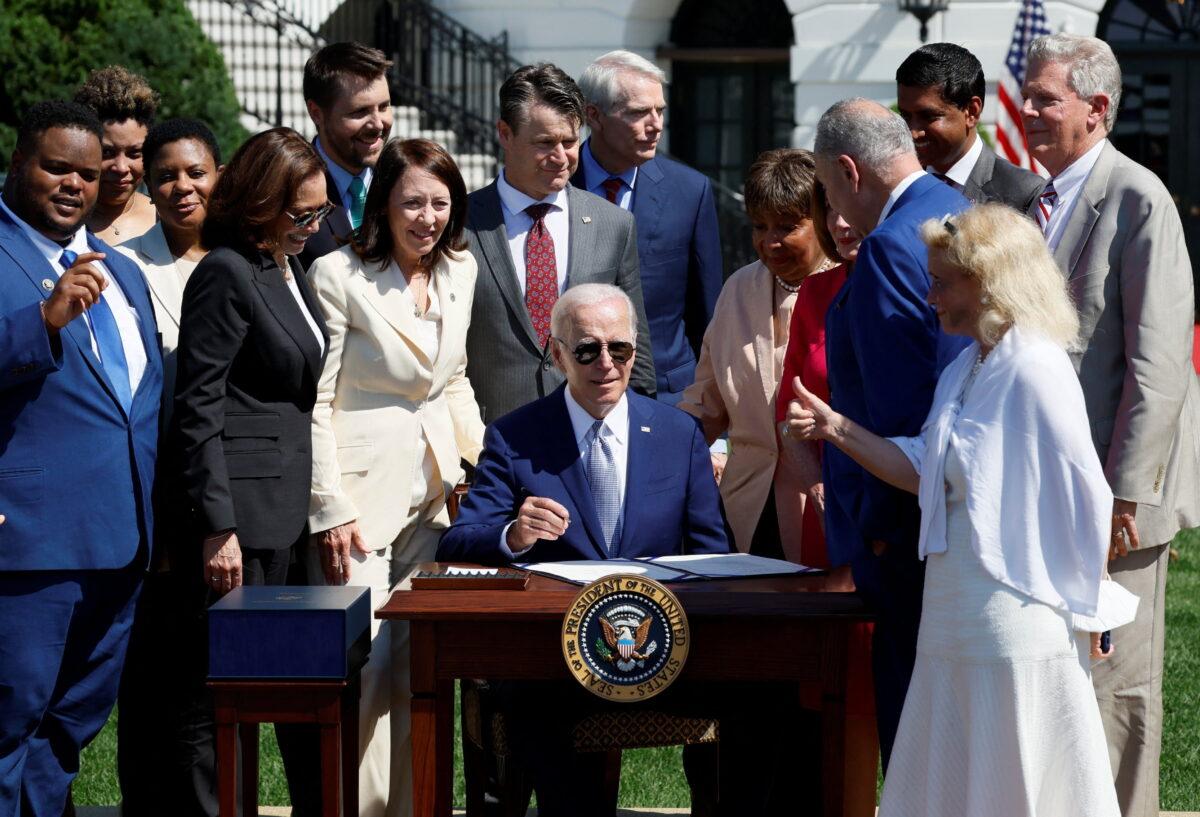 President Joe Biden signs the CHIPS and Science Act of 2022 alongside Vice President Kamala Harris, House Speaker Nancy Pelosi, and Joshua Aviv, founder and CEO of SparkCharge, on the South Lawn of the White House in Washington on Aug. 9, 2022. (Evelyn Hockstein/Reuters)