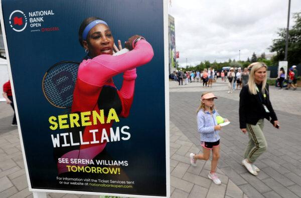 People pass a poster advertising the match of veteran tennis player Serena Williams, who said that she plans to retire after the 2022 U.S. Open, outside a stadium at the National Bank Open in Toronto on Aug. 9, 2022. (Chris Helgren/Reuters)