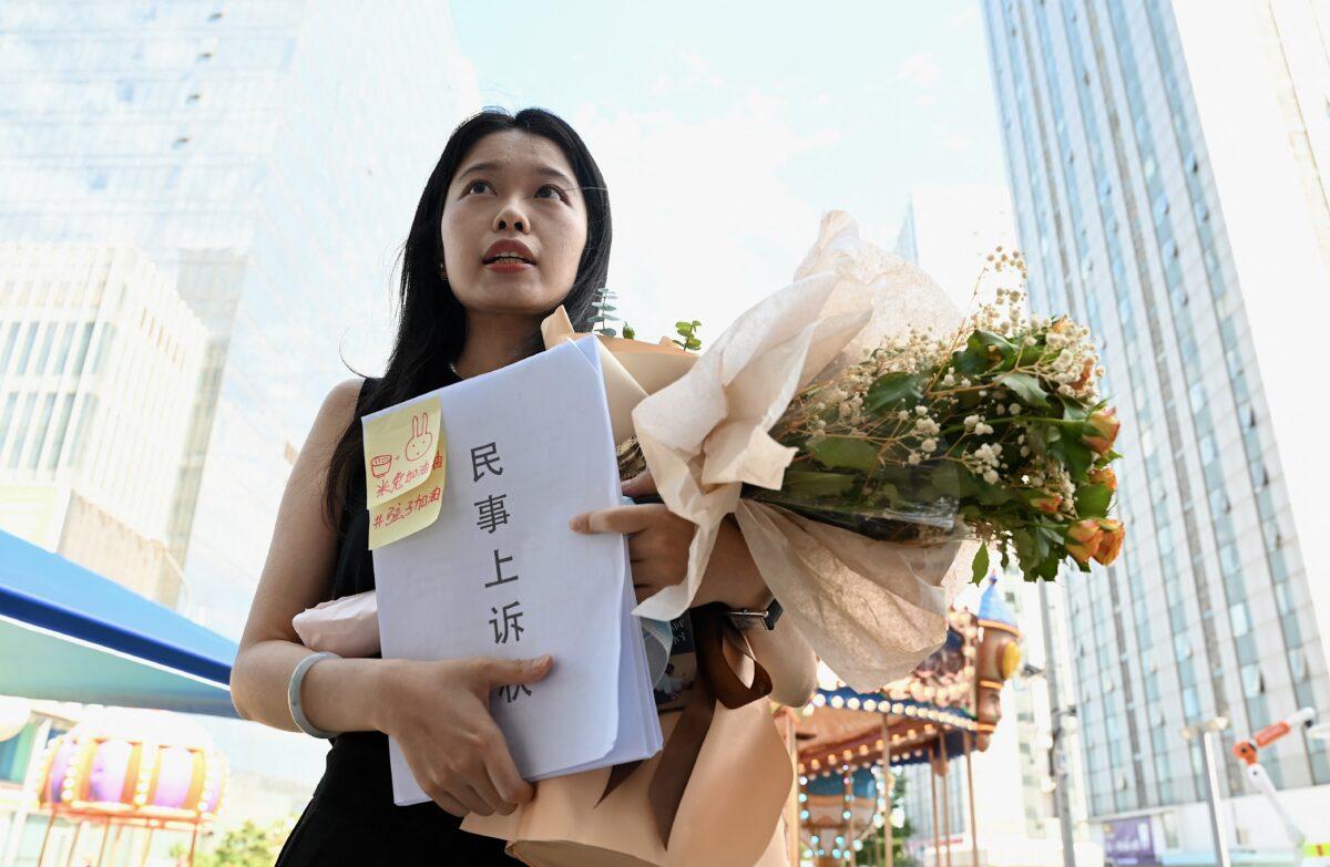 Zhou Xiaoxuan, also known as Xianzi, holds a bouquet of flowers as she arrives to attend a hearing in her sexual harassment case against prominent television host Zhu Jun at the Beijing No. 1 Intermediate People's Court in Beijing on Aug. 10, 2022. (Noel Celis/AFP via Getty Images)