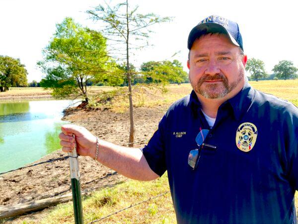Cattle rancher Brad Allison is also the chief of police in Canton, Texas. Here, he stands in front of a watering hole now overgrown with algae because of the heat and drought conditions plaguing much of the state on Aug. 11, 2022. (Allan Stein/The Epoch Times)