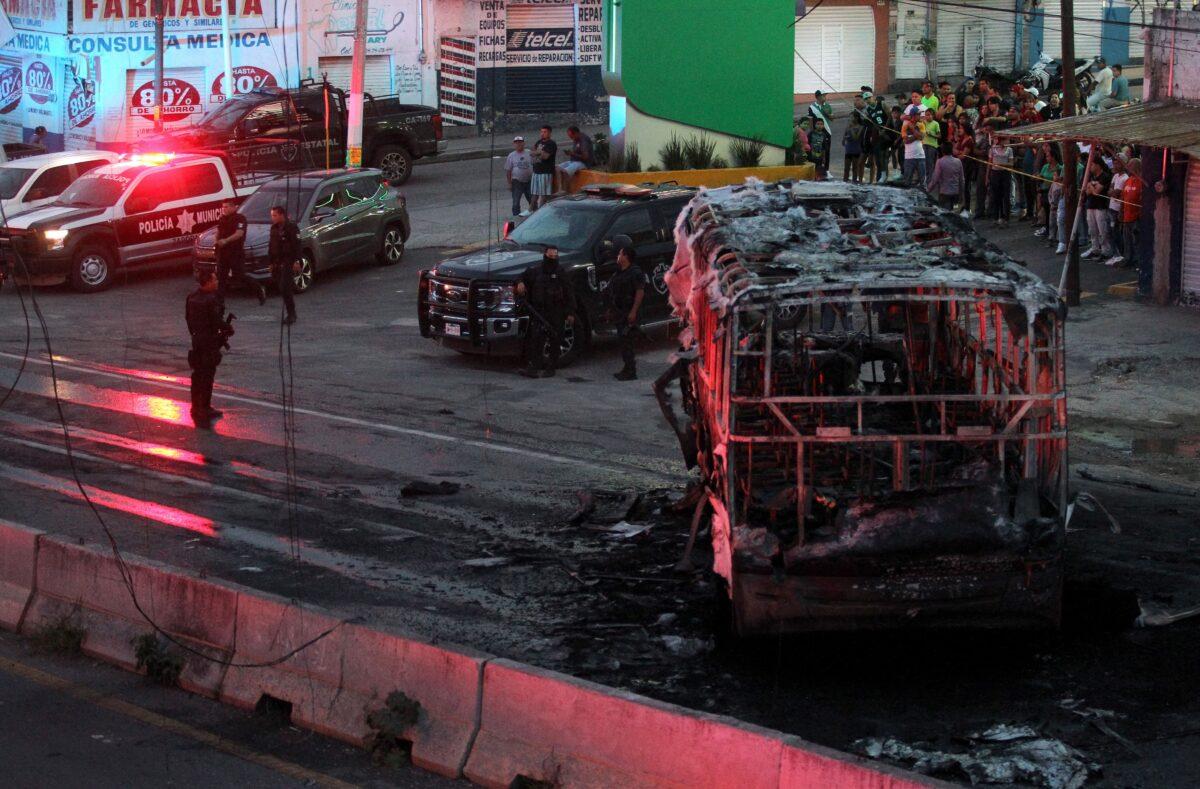 Members of the State Prosecutor's Office and Municipal Police guard the area where gang members set a bus on fire blocking a highway to prevent authorities from chasing them while they were clashing with another gang in Zapopan, Jalisco State, Mexico, on Aug. 9, 2022. (Ulises Ruiz/AFP via Getty Images)