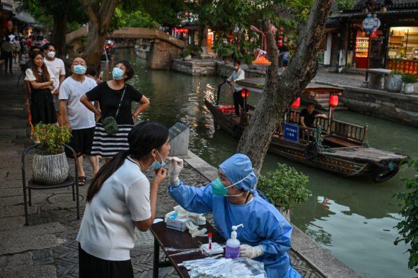 A health worker takes a swab sample from a woman to test for COVID-19 in the Zhujiajiao ancient water town in Shanghai, China on July 31, 2022. (Hector Retamal/AFP via Getty Images)