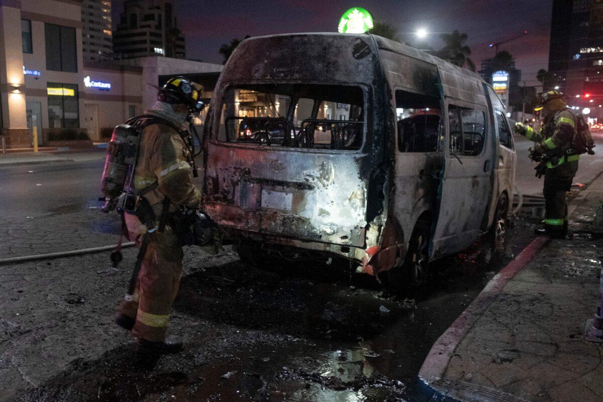 Firefighters work at the scene of a burnt collective transport vehicle after it was set on fire by unidentified individuals in Tijuana, Baja California state, Mexico, on Aug. 12, 2022. (Guillermo Arias/AFP via Getty Images)