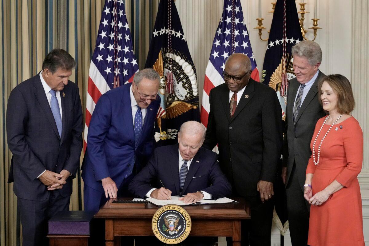 President Joe Biden signs the Inflation Reduction Act as Democrat lawmakers look on at the White House in Washington, on Aug. 16, 2022. (Drew Angerer/Getty Images)