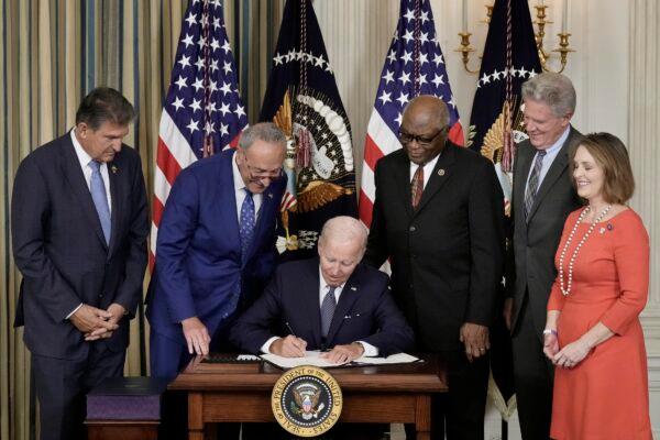 President Joe Biden (C) signs the Inflation Reduction Act with (L-R) Sen. Joe Manchin (D-W.Va.), Senate Majority Leader Chuck Schumer (D-N.Y.), House Majority Whip James Clyburn (D-S.C.), Rep. Frank Pallone (D-N.J.), and Rep. Kathy Castor (D-Fla.) in the State Dining Room of the White House in Washington on Aug. 16, 2022. (Drew Angerer/Getty Images)