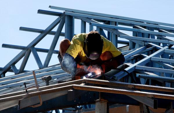 A welder works on the roof of a new house construction in Karratha. Australia, on June 17, 2008. (Greg Wood/AFP via Getty Images)