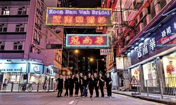 The last night the neon sign of the long-established "Koon Nam Wah" in Yau Ma Tei was displayed, on Aug. 16, 2022. Staff members of Koon Nam Wah take a group photo with the neon signs. (TM Chan/The Epoch Times)