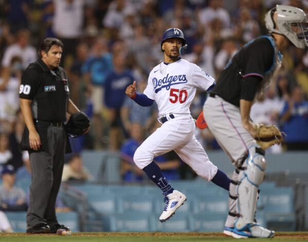 Mookie Betts #50 of the Los Angeles Dodgers scores a run behind Jacob Stallings #58 of the Miami Marlins and in front of umpire Mark Ripperger #90, to take a 2–1 lead, during the eighth inning at Dodger Stadium in Los Angeles, on August 19, 2022. (Harry How/Getty Images)