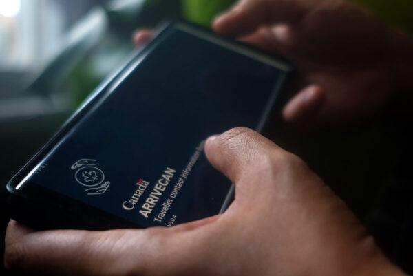 A person holds a smartphone set to the opening screen of the ArriveCan app, which requires people to declare their vaccination status to be able to enter Canada. (Giordano Ciampini/The Canadian Press)